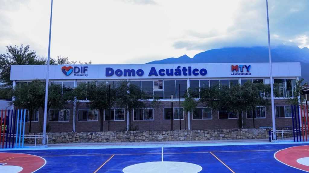 Dif Monterrey Building Labeled Domo Acuático with Mty Sign, Flanked by Trees, in Front of a Colorful Outdoor Basketball Court. - Adelante Mty