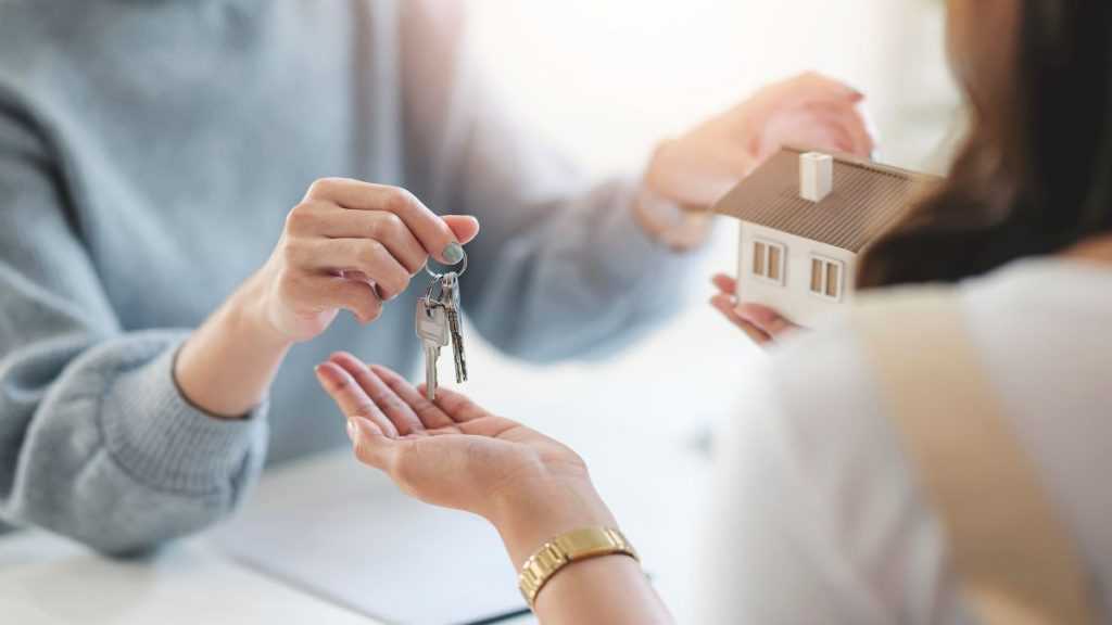 Key Handoff During a Real Estate Transaction, with a Small Model House in View - Adelante Mty