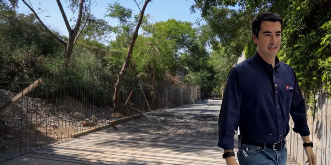 Rehabilitación-de-pluvial-obras-publicas-monterery - Adelante Mty Man in a Navy Shirt and Jeans Walks Along a Sunny, Tree-lined Walkway with a Wire Fence on the Left, Suggesting a Construction Area. - Adelante Mty