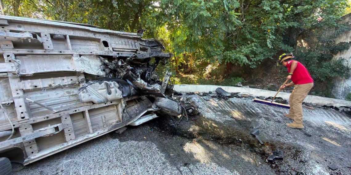 Large Overturned Heavy Vehicle Crushed on Its Side, Debris Scattered on the Road, Worker in Red Shirt and Helmet Sweeping Nearby - Adelante Mty