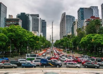 Busy City Boulevard Lined with Green Trees and Tall Office Buildings, Heavy Traffic in Both Directions on a Cloudy Day. - Adelante Mty