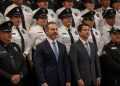 Two Men in Suits Stand in Front of a Line of Uniformed Police Officers at a Formal Event.", - Adelante Mty