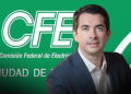 Man in a Navy Suit Poses in Front of a Green Cfe Backdrop with the Comisión Federal De Electricidad Logo. - Adelante Mty