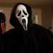 Person in a Black Hooded Cloak Wearing a Ghostface Mask Raises a Blood-stained Knife in a Dimly Lit Room. - Adelante Mty